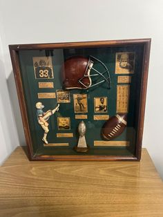 an old football helmet and other memorabilia is displayed in a shadow box on a wooden table