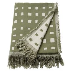 a green and white throw blanket with fringes on the bottom, in front of a white background