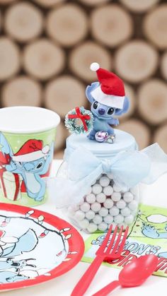 Adding a mini Santa Hat, a mini wreath, and mini jingle bells to a Stitch figurine made the perfect mini candy jar favor topper to match some Holiday Stitch partyware! Get details and more DIY favor ideas now at www.fernandmaple.com.