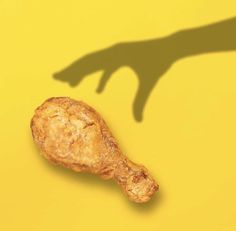 the shadow of a hand holding a piece of food in front of a yellow background