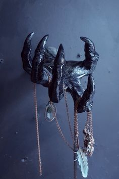 a black sculpture is hanging on the wall and has chains attached to it's sides