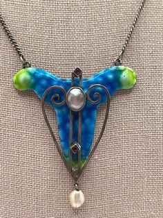 "This is a stunning antique British arts & crafts blue and green enamel, mother of pearl, and paste necklace.  The necklace is unmarked, it x-rayed as around 700 silver when tested by an XRF analyzer.  The necklace is in very good antique condition, upon close inspection, the silver swirl to the right of the mother of pearl appears to have become unsoldered from next to the mother of pearl setting, there is a tiny dot of enamel missing on the top right, a small area of enamel missing close to the mother of pearl center but mostly hidden by the mother of pearl, and there is minor enamel loss around the edges.  The necklace measures approximately 15 1/2\" long and the pendant measures approximately 2 1/8\" long by 1 3/4\" wide and weighs approximately 13.92 grams. - For international custome Unique Blue Necklace With Inlay, Antique Enamel Necklace Hallmarked, Antique Enamel Necklace With Hallmark, Antique Enamel Hallmarked Necklaces, Vintage Turquoise Enamel Jewelry, Vintage Blue Enamel Necklace, Antique Blue Cabochon Necklace, Collectible Blue Inlay Necklace, Victorian Blue Pendant Necklace