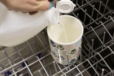 someone pouring milk into a dishwasher with their hand on the cup and another person holding a bottle