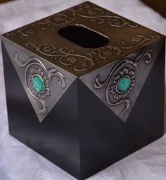 a black and gold box with green eyes on it's lid sitting on a white sheet