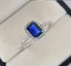 an engagement ring with a blue stone surrounded by white cubicles in a velvet box