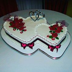 two heart shaped cakes with red flowers and hearts on the top are sitting on a white table