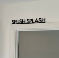 a black sign that says splash on the wall above a white door in a room