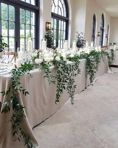 a long table is set up with candles and greenery for an elegant wedding reception