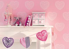 there is a pink room with hearts on the wall and a white fireplace mantel