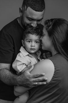 a black and white photo of a man holding a little boy with his hands on his chest