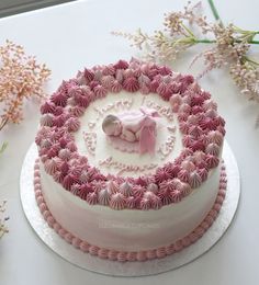 a pink and white cake with a baby's name on it, surrounded by flowers