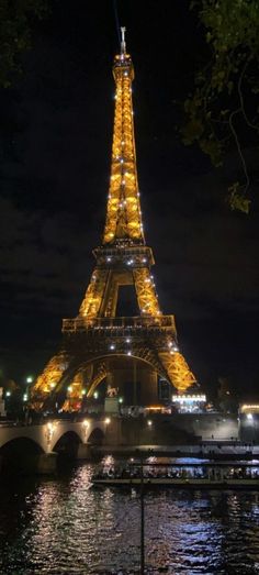 the eiffel tower lit up at night with lights reflecting in the water below