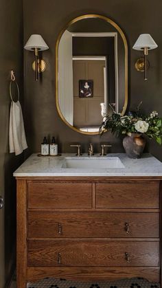 a bathroom with a sink, mirror and lights on the wall next to a toilet