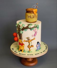 a winnie the pooh birthday cake on a wooden stand