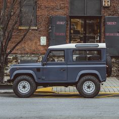 a blue jeep parked in front of a brick building on the side of the road