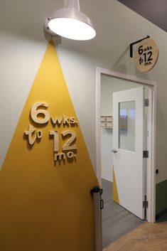 the entrance to an office building with yellow and white letters on the wall, next to a door