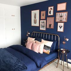 a bedroom with blue walls and pictures on the wall above the bed, along with a small side table