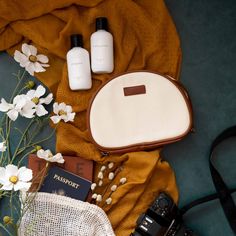 the contents of a travel bag laid out on a blanket with flowers and other items