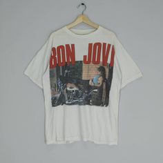 a white t - shirt with the words bon jovi on it hanging from a hanger