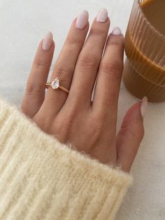 a woman's hand with a ring on her finger next to a glass of coffee