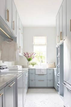 a white kitchen with blue cabinets and stainless steel appliances in the center is an open window