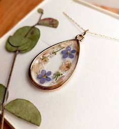 "A beautiful and unique Botanical inspired terrarium necklace with real forget me not flowers and baby breath flowers (gypsophila)  For memories of a close one, for true love and to show someone you will never forget them  💕 The flower is encapsulated in a crystal clear Resin which is Non-toxic, No VOCs, No fumes, No solvents, Non-flammable, Non-hazardous, No BPA.  The necklace chain is gold plated solid brass or stamped 14k gold filled chain as shown in last photo. This chain is much more long lasting and delicate. (this one is shown in the last photo)  The pendant is 1 inch in width and length.  A cute and eco friendly gift for yourself or a loved one. 🌼 So someone you love can bring spring with them wherever they go 🌼  The necklace comes in a lovely little box, hand stamped with the Dainty Keepsake Necklace With Adjustable Chain, Dainty Necklace With Adjustable Chain For Keepsake, Dainty Birth Flower Jewelry For Keepsake, Teardrop Pressed Flowers Jewelry Gift, Delicate Pressed Flower Pendant Jewelry, Delicate Flower Pendant Jewelry With Pressed Flowers, Minimalist Pressed Flower Pendant Jewelry, Teardrop Necklace With Natural Inclusions For Gift, Pressed Flowers Keepsake Jewelry