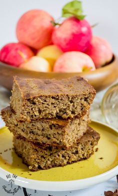 three pieces of banana bread on a plate with apples in the backgroung