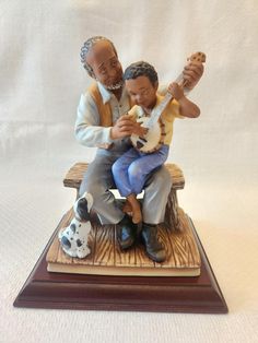 a figurine of two men sitting on a bench with a guitar and dog