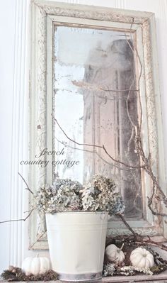 a white potted plant sitting on top of a table next to a mirror and other decorations