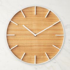 a wooden clock with white hands on a marble surface