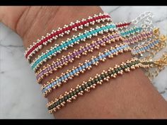 several different colored bracelets on a person's arm with gold, silver and blue beads