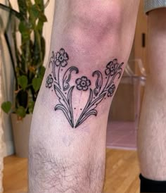 a man's leg with flowers on it and the word love written in black ink