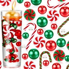 a glass filled with candy canes next to christmas balls and candies on a white background