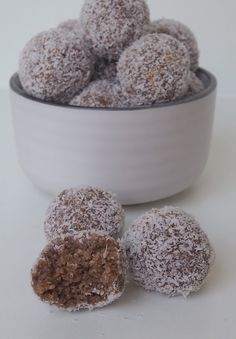 powdered sugar covered donuts in a bowl on a white counter top next to it