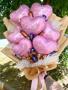 a bouquet of pink heart shaped balloons with the words camofi on them in front of a tree