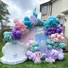 there are many balloons in the shape of mermaids and seashells on this lawn