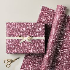 two wrapping paper with scissors next to them on top of a white tablecloth covered in red and white polka dots