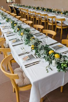 a long table is set with place settings and yellow chairs