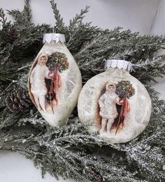 two christmas baubles decorated with images and pine cones