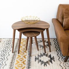 two wooden tables sitting on top of a rug next to a brown chair and ottoman