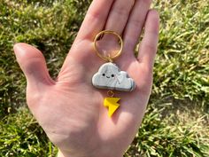 a hand holding a keychain with a cloud and lightning on it