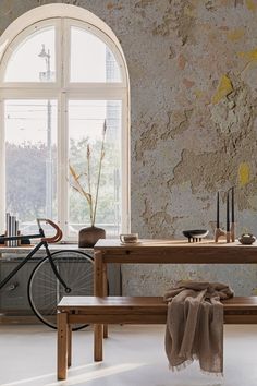 a table and bench in front of a window with a bicycle parked next to it