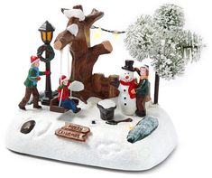 a group of figurines are standing in the snow near a tree and lamp post