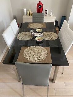 a dining room table with chairs and a vase on the wall in the corner behind it