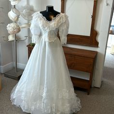 a wedding dress on display in front of a mirror and mannequin behind it