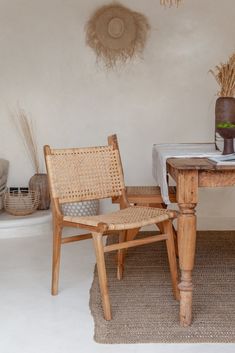 two wooden chairs sitting next to each other on top of a rug in front of a table