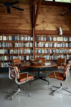 an office with a table and chairs in front of bookshelves