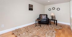 a living room with white walls and wood flooring on the hard wood floor is decorated with decorative rugs