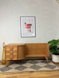 a wooden cabinet sitting on top of a hard wood floor next to a potted plant