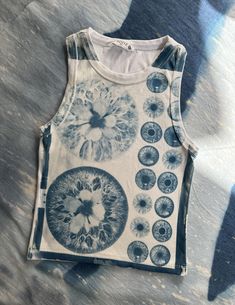 a tank top with an image of flowers and circles printed on the front, sitting on a bed